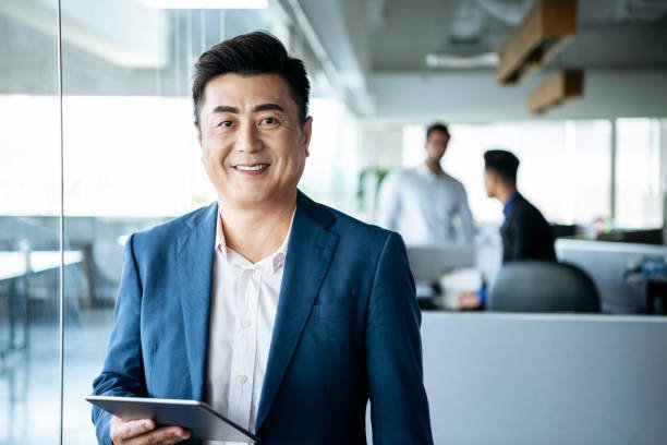 Portrait of Asian man in his 50s in modern office and cheerful expression